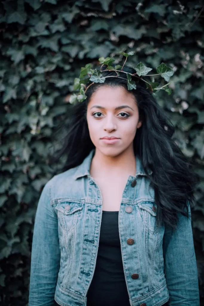 Woman in denim jacket with ivy crown in front of leafy background