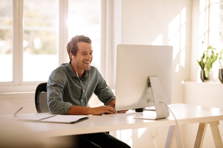 Person working happily at a computer in a bright office.