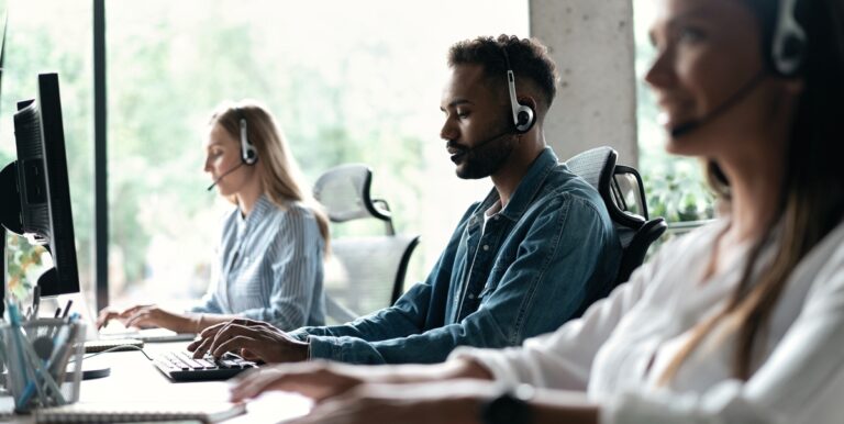 Customer support team working with headsets in a modern office setting.