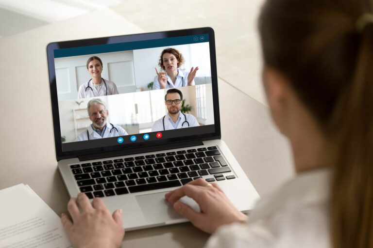 Person engaging in a virtual meeting with healthcare professionals on a laptop.