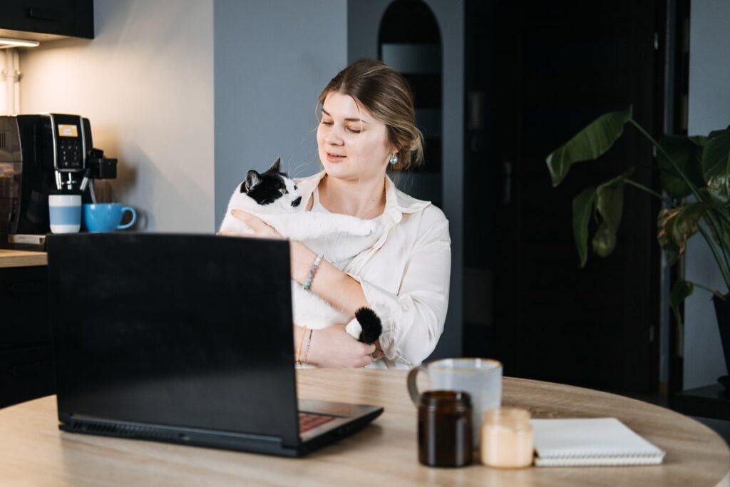 Female vet holding her cat while working on a computer as Virtual assistant in healthcare