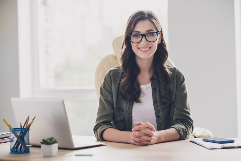 Happy virtual assistant on real estate sitting at a desk ready to work.