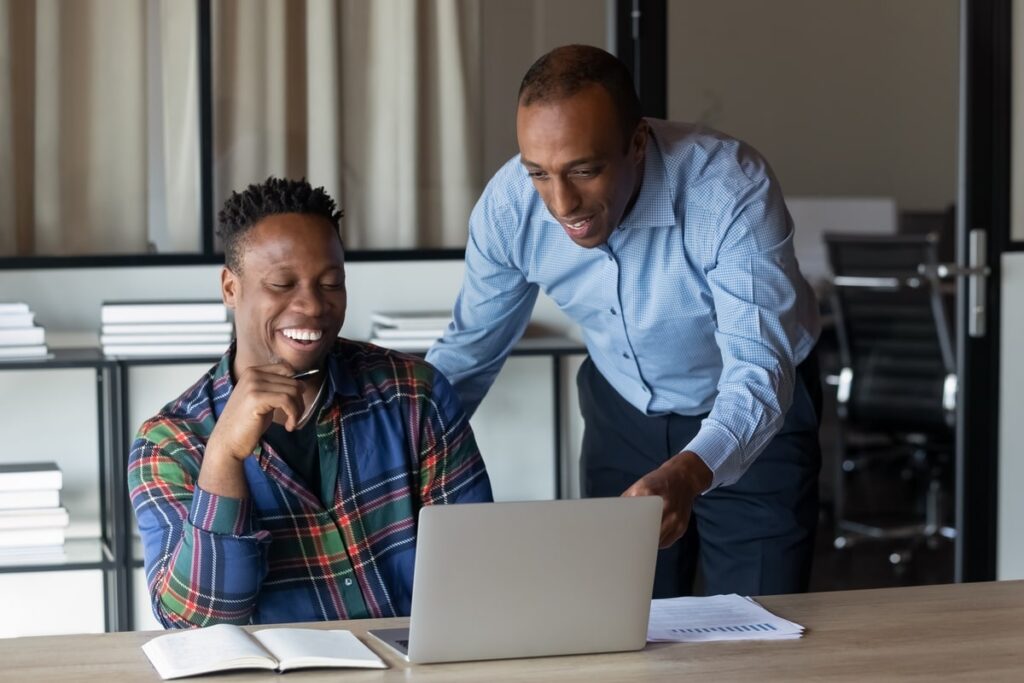 Happy virtual assistant real estate talking with his boss while working on laptop.