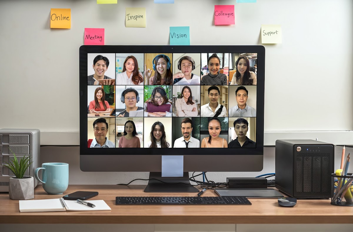 Virtual team meeting on a computer screen with multiple participants in an organized home office setup.