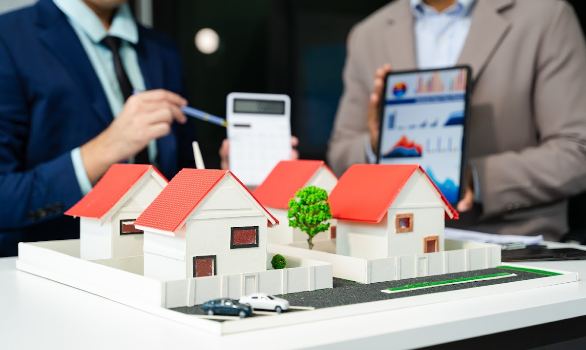 Real estate agents analyzing housing market data with a miniature property model.