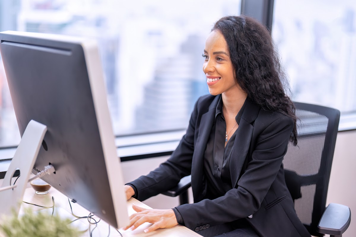 A smiling female administrative assistant, working on a computer in a modern office.