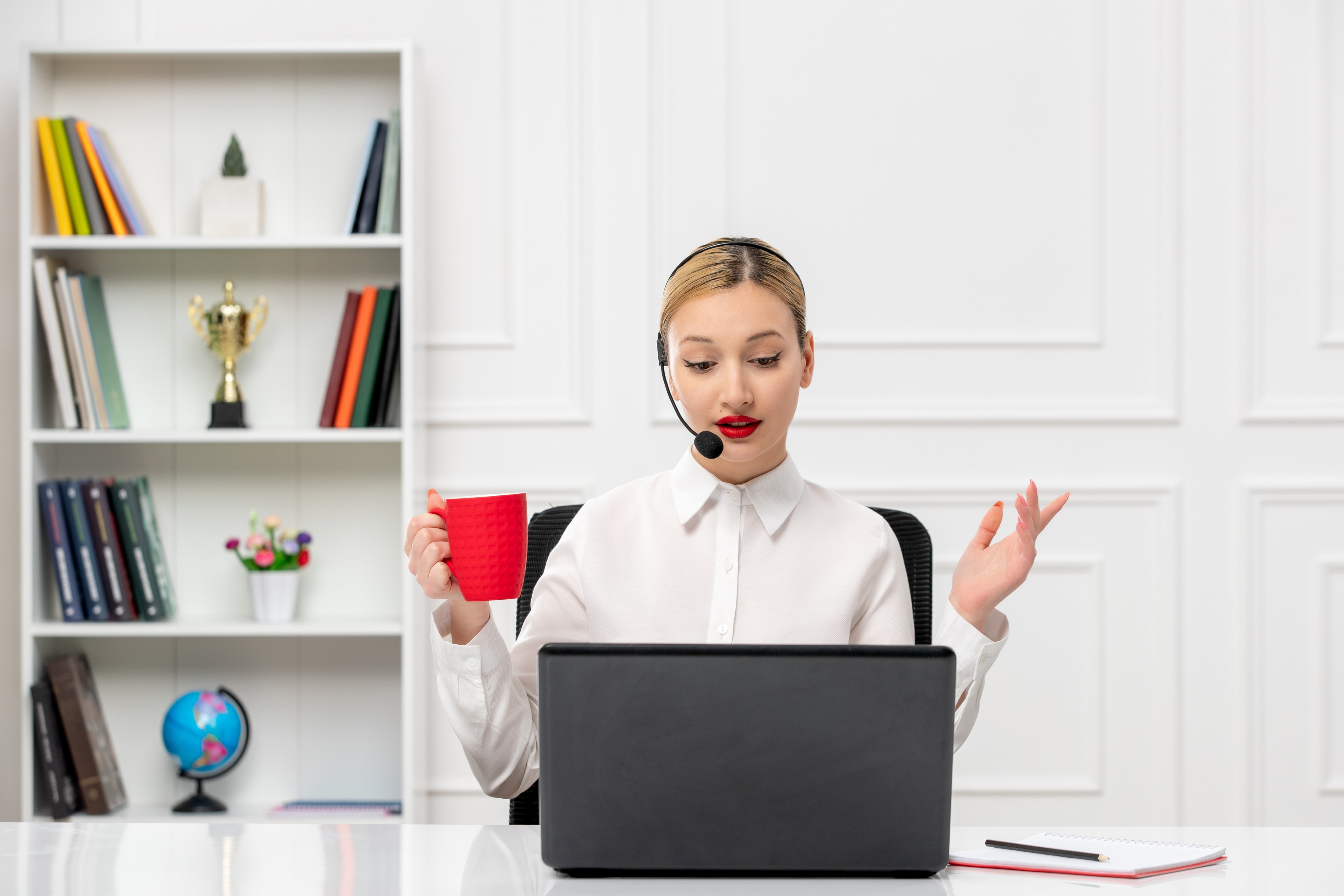 Woman with headset working on laptop drinking coffee