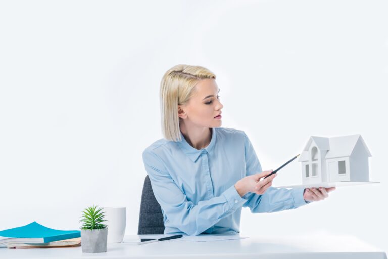 Woman holding white house model pointing pen