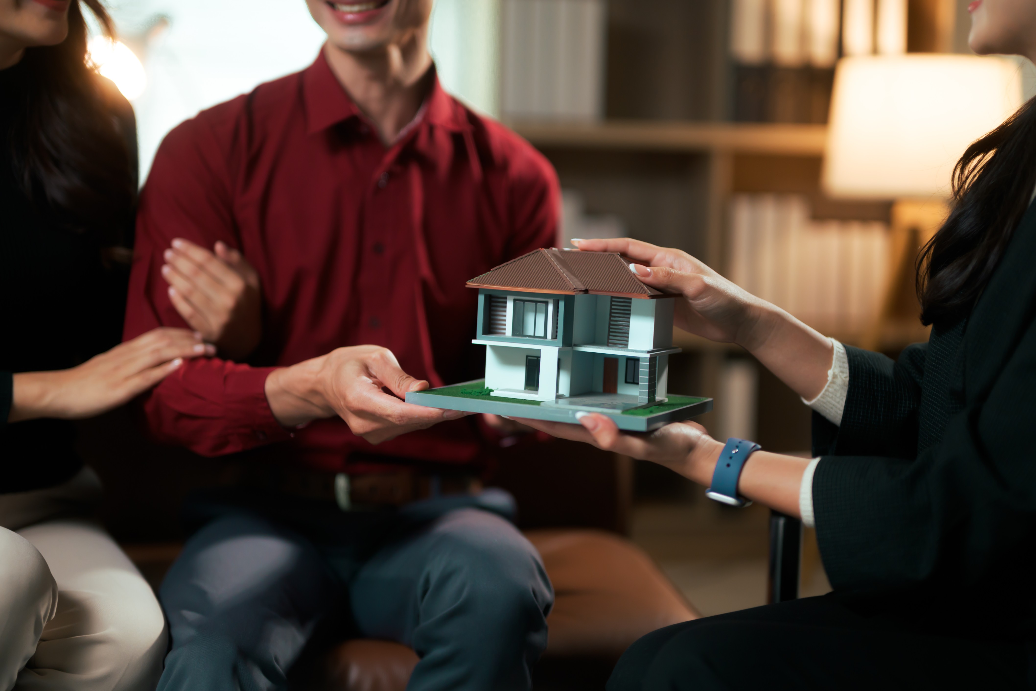 Couple holding miniature house model indoors