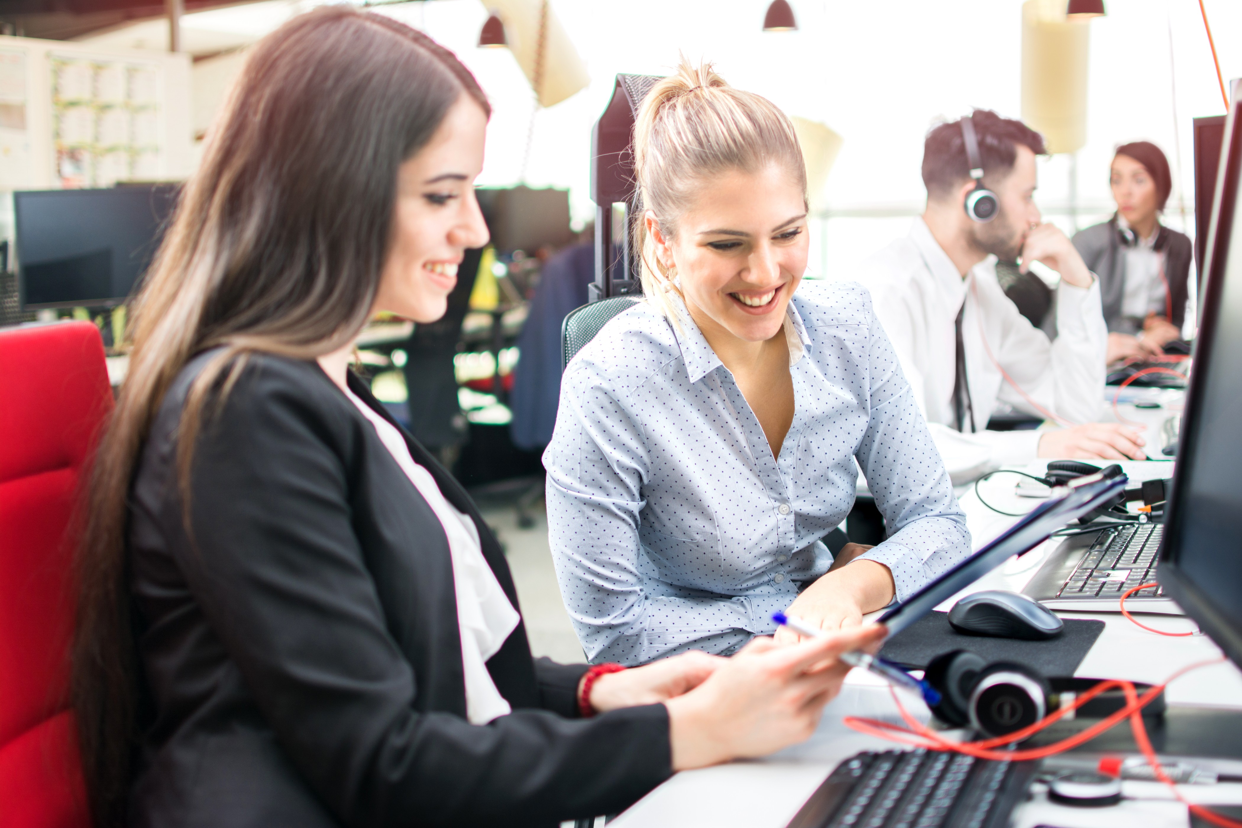 Women collaborating at office desk with smartphone