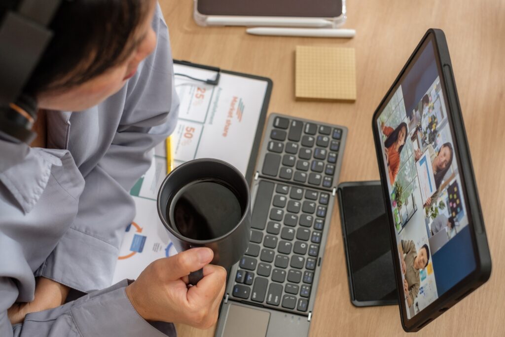 Person drinking coffee during virtual meeting