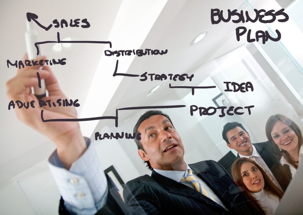 Businessman writing business plan on glass panel