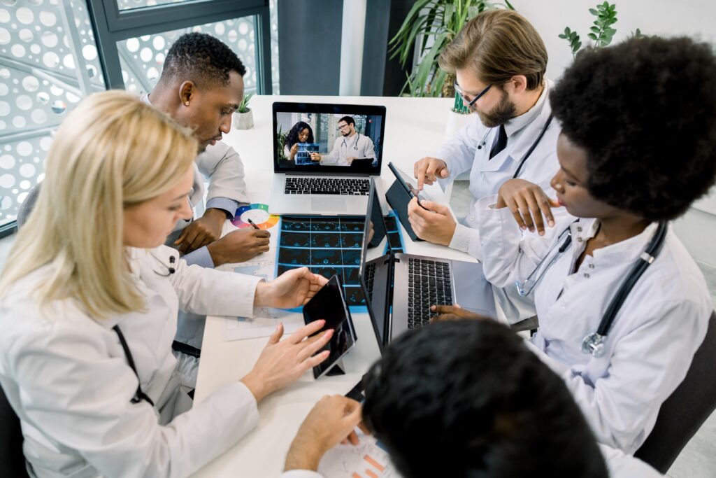 Doctors reviewing brain scans on laptop and tablet