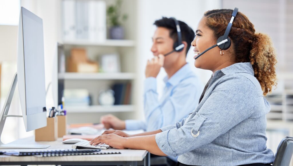 Customer service agents using headsets at computers
