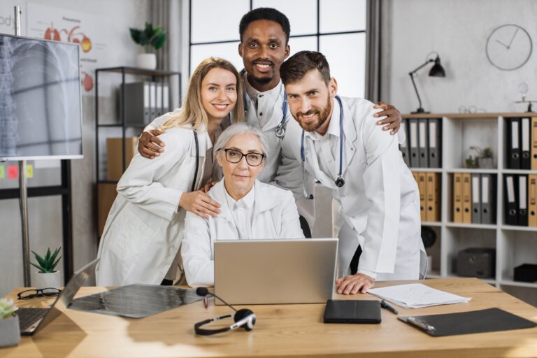 Medical team smiling around laptop in office
