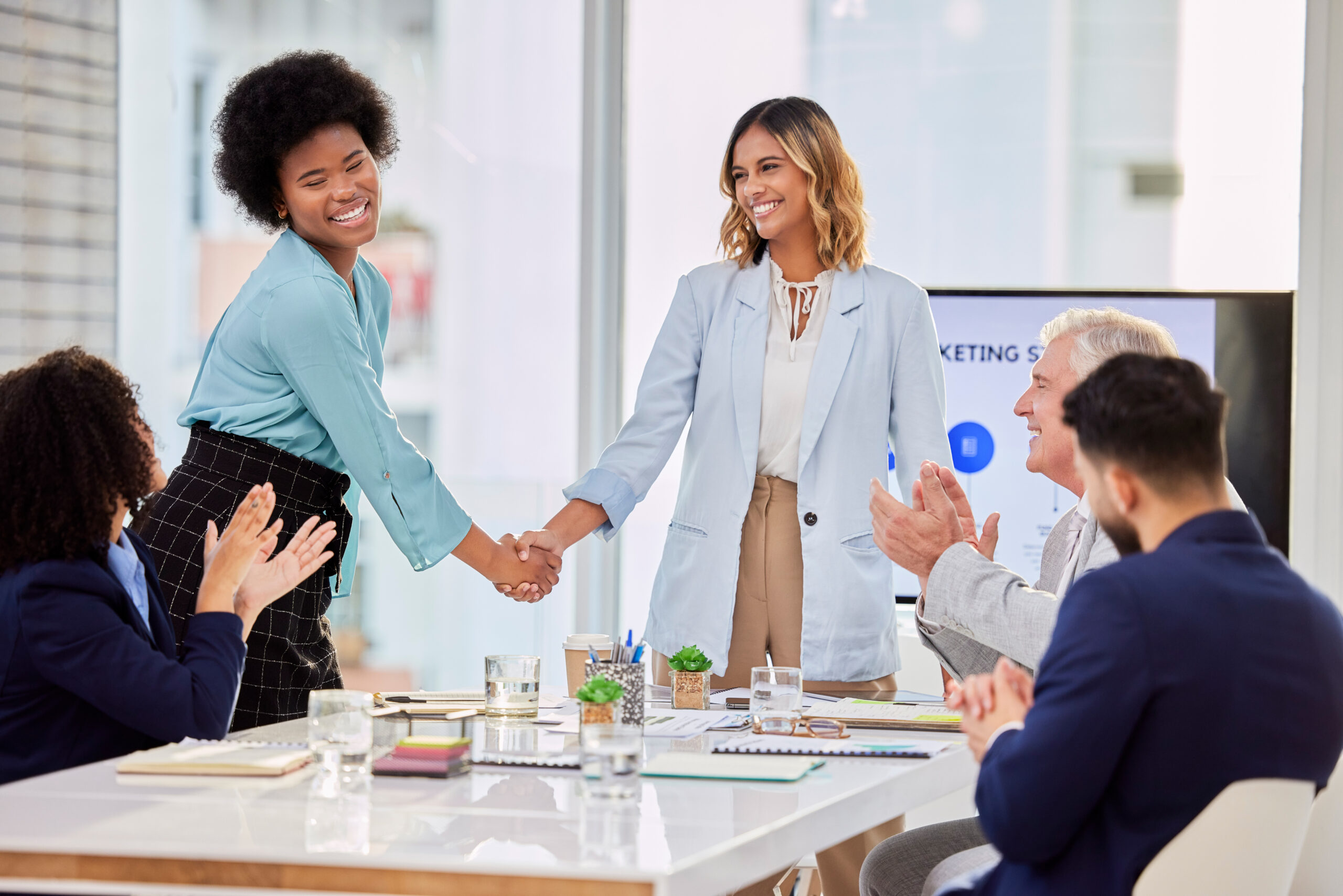 Businesswomen shaking hands in office meeting