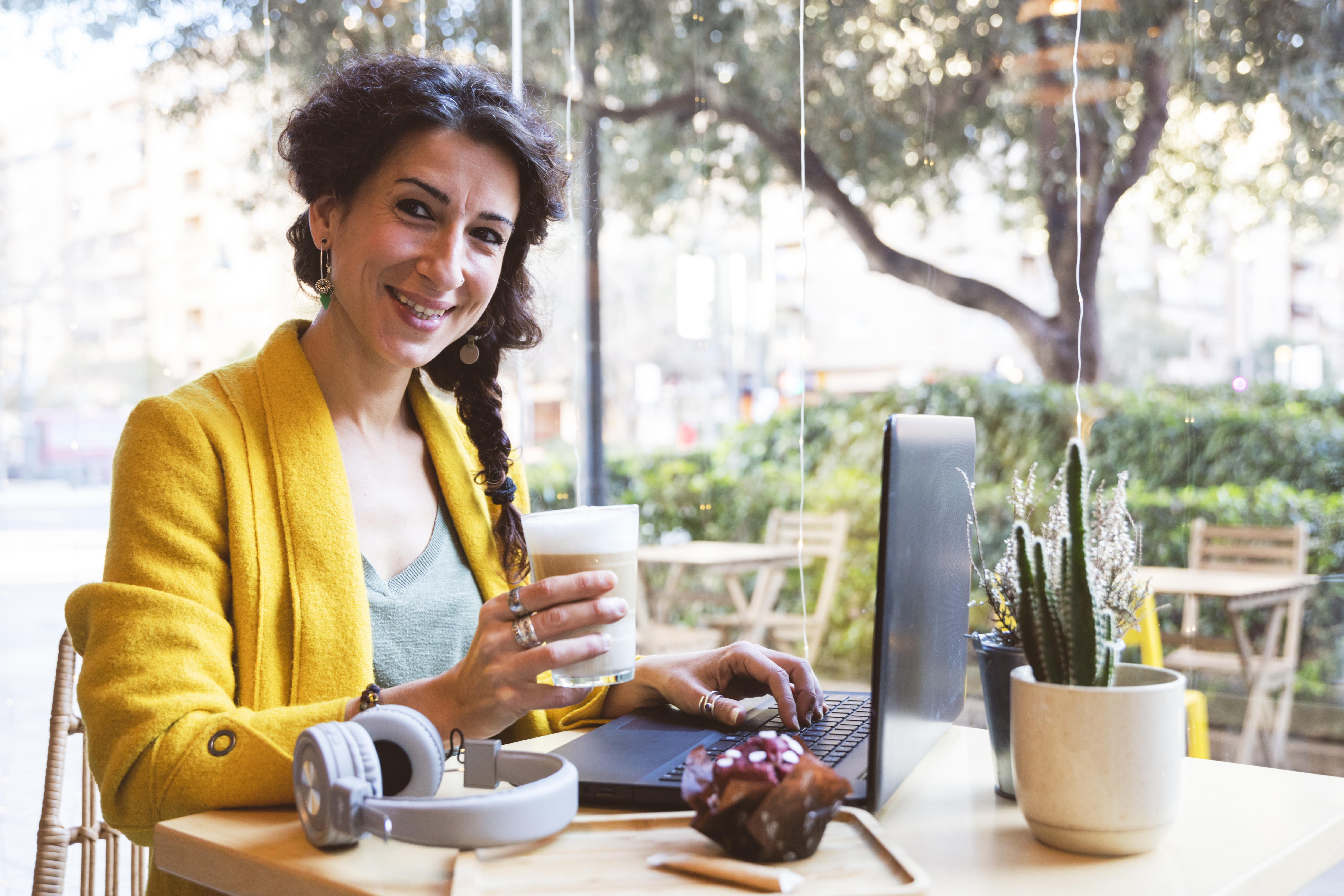Woman working on laptop drinking latte in cafe