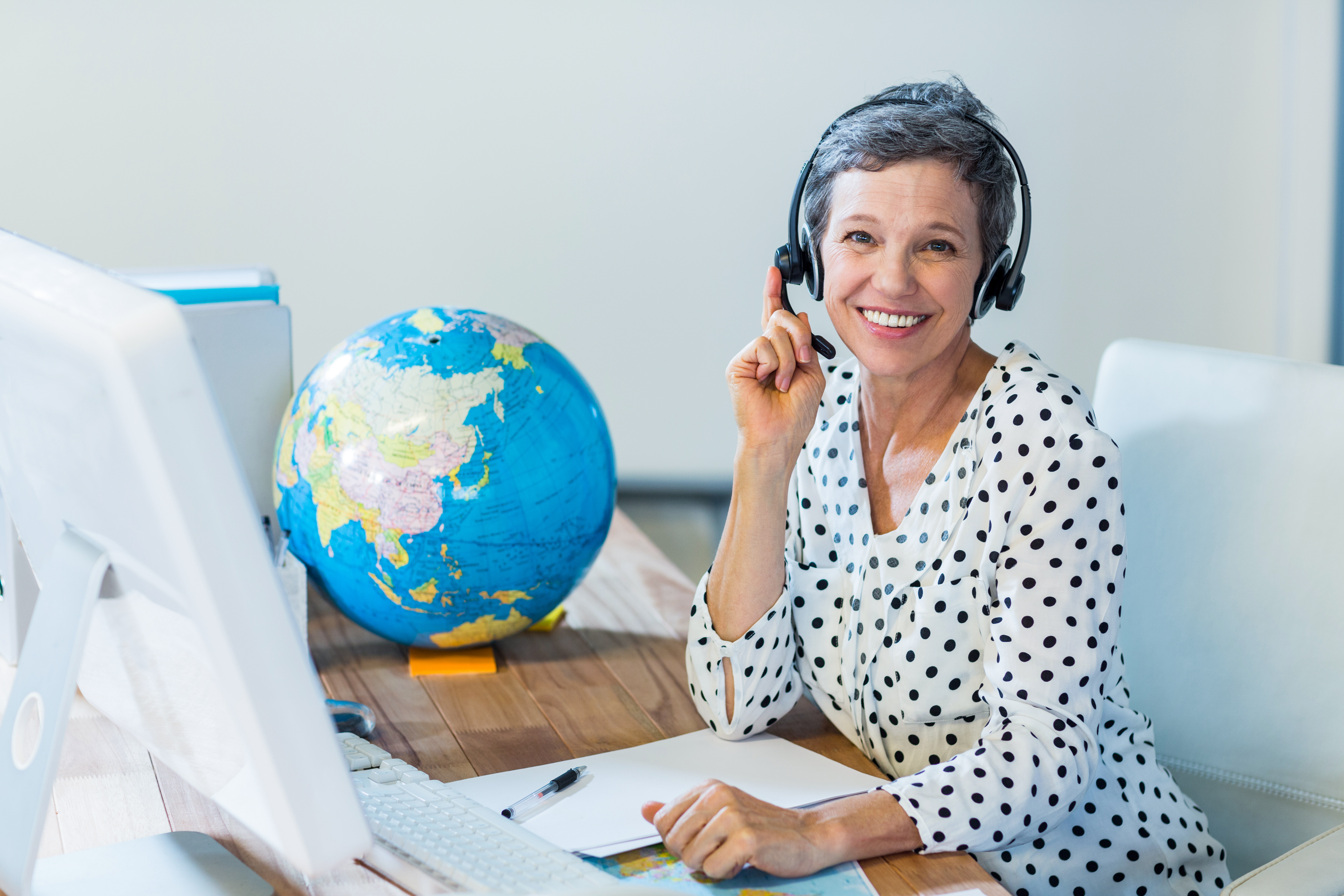 Woman with headset at desk and globe