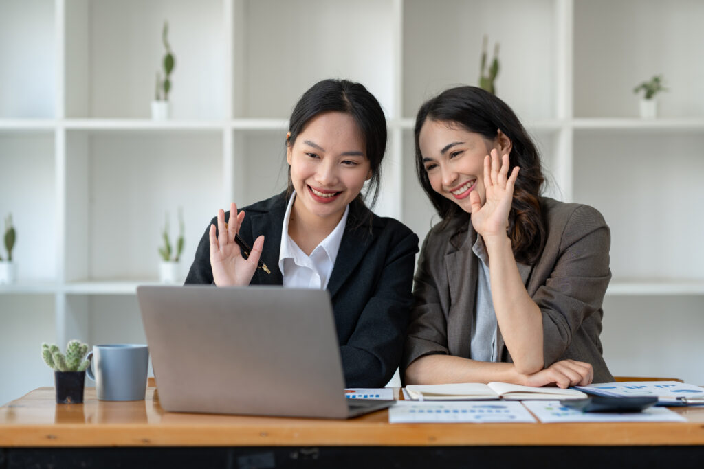 Women waving on video call laptop